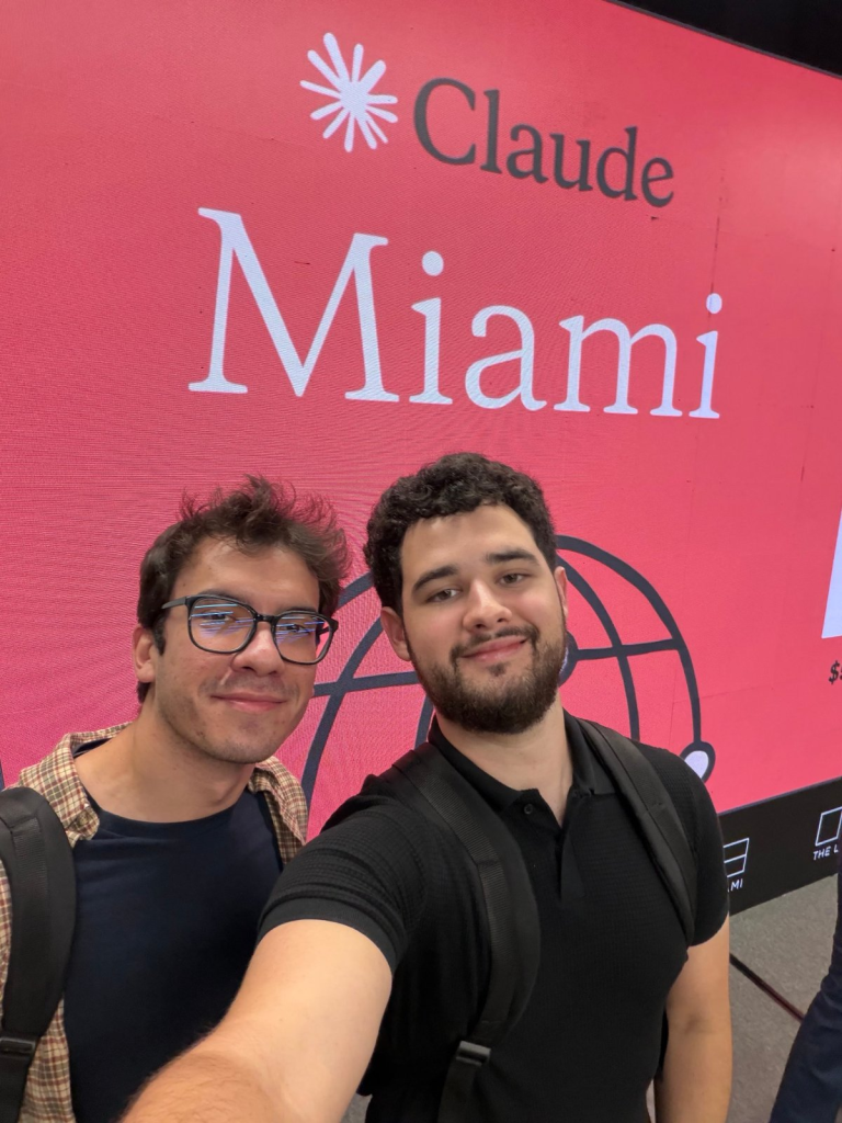 Two AI vs Brain workshop participants in front of the Claude Miami event screen at The LAB Miami.